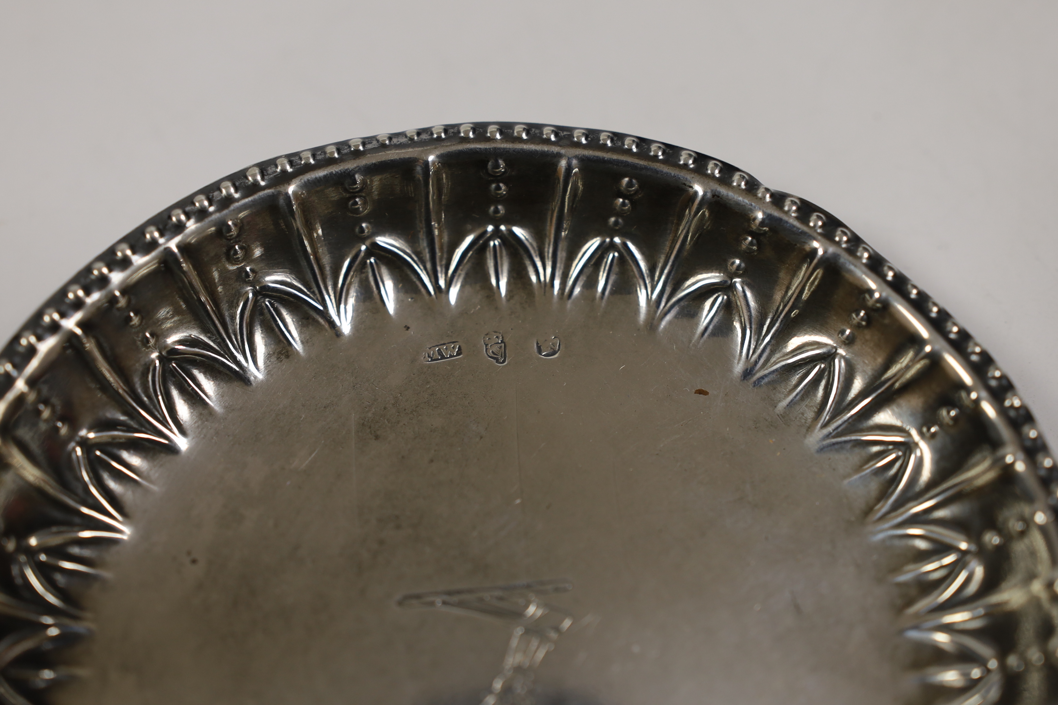 A George III Irish silver small dish, with repousse border and engraved crest, by Matthew West, Dublin, circa 1780, 12.1cm, 2,6oz.